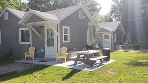 A two-story house with a covered porch, a picnic table, and outdoor seating. - The Beach House Cottage (Fort Gratiot Twp)