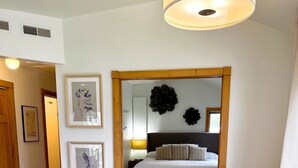 A dining area with a round table and four chairs, a bed with a dark headboard and pillows, and a wall with two framed botanical prints. - Door county cottage (Sturgeon Bay)