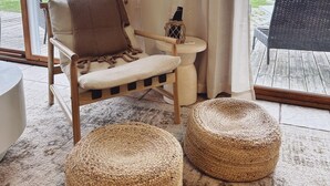 A cozy room with a wooden chair, a small round table, and two woven ottomans. - Door county cottage (Sturgeon Bay)