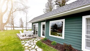 A house with a stone pathway leading to a patio with outdoor furniture. - Door county cottage (Sturgeon Bay)