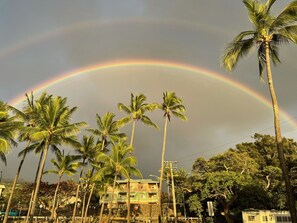 A residential area with palm trees and a building with a balcony. - Beach Front Condo (Ocean View), Best Snorkeling/Surfing. (Kailua-Kona)