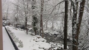 A snow-covered landscape with a river, trees, and a fence. - Cascading Creek / Gatehouse Condos / 2BR / 1st floor / no steps (Gatlinburg)