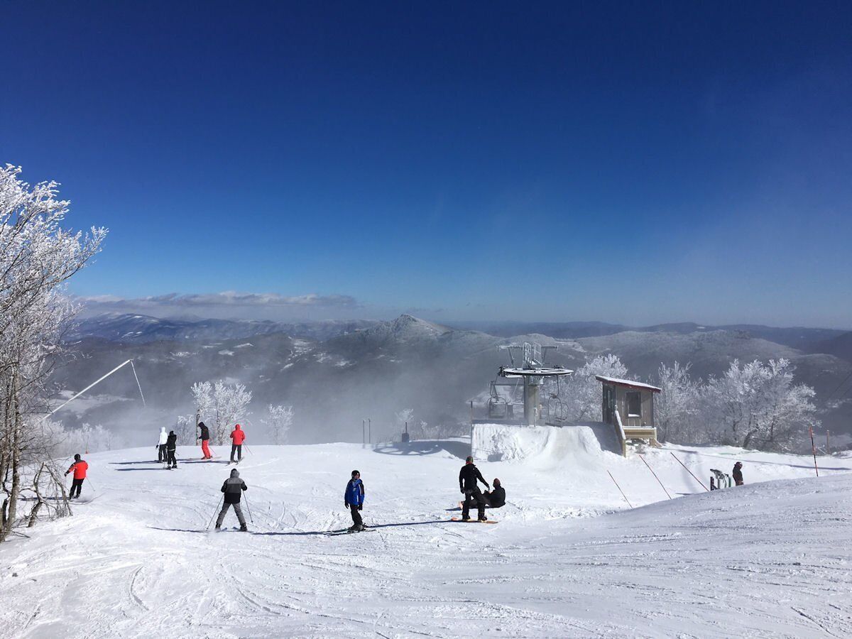 A snowy ski slope with skiers and a ski lift.