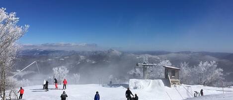 A snowy ski slope with skiers and a ski lift.