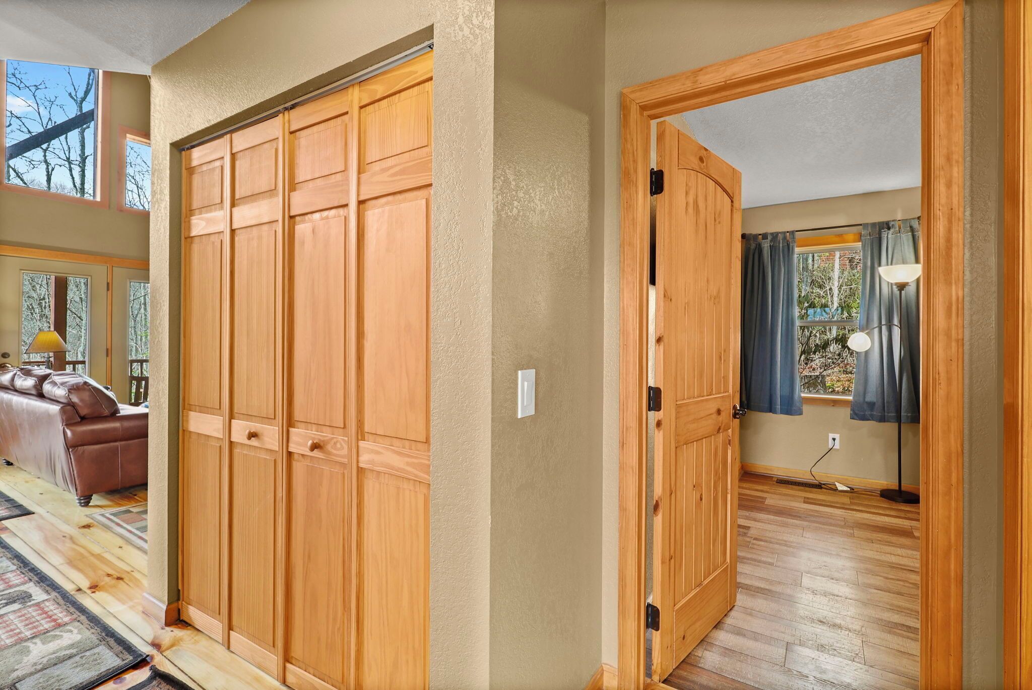 Un pasillo con puertas de madera que dan a una habitación con ventana y lámpara.