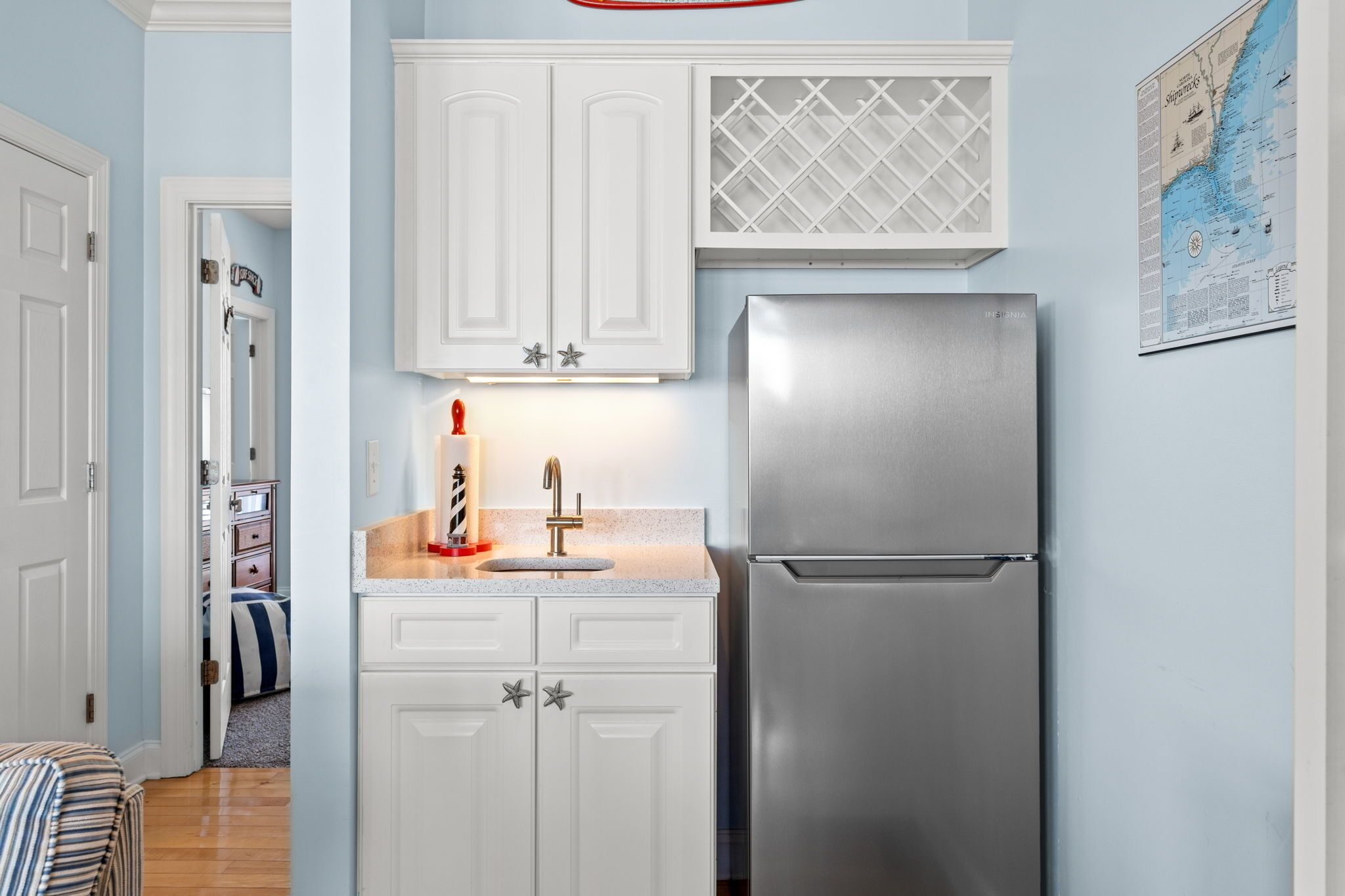 A kitchen with white cabinets, a stainless steel refrigerator, and a map on the wall.