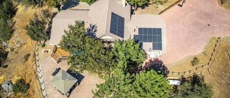 Una casa moderna con paneles solares, un porche cubierto y un patio cercado.