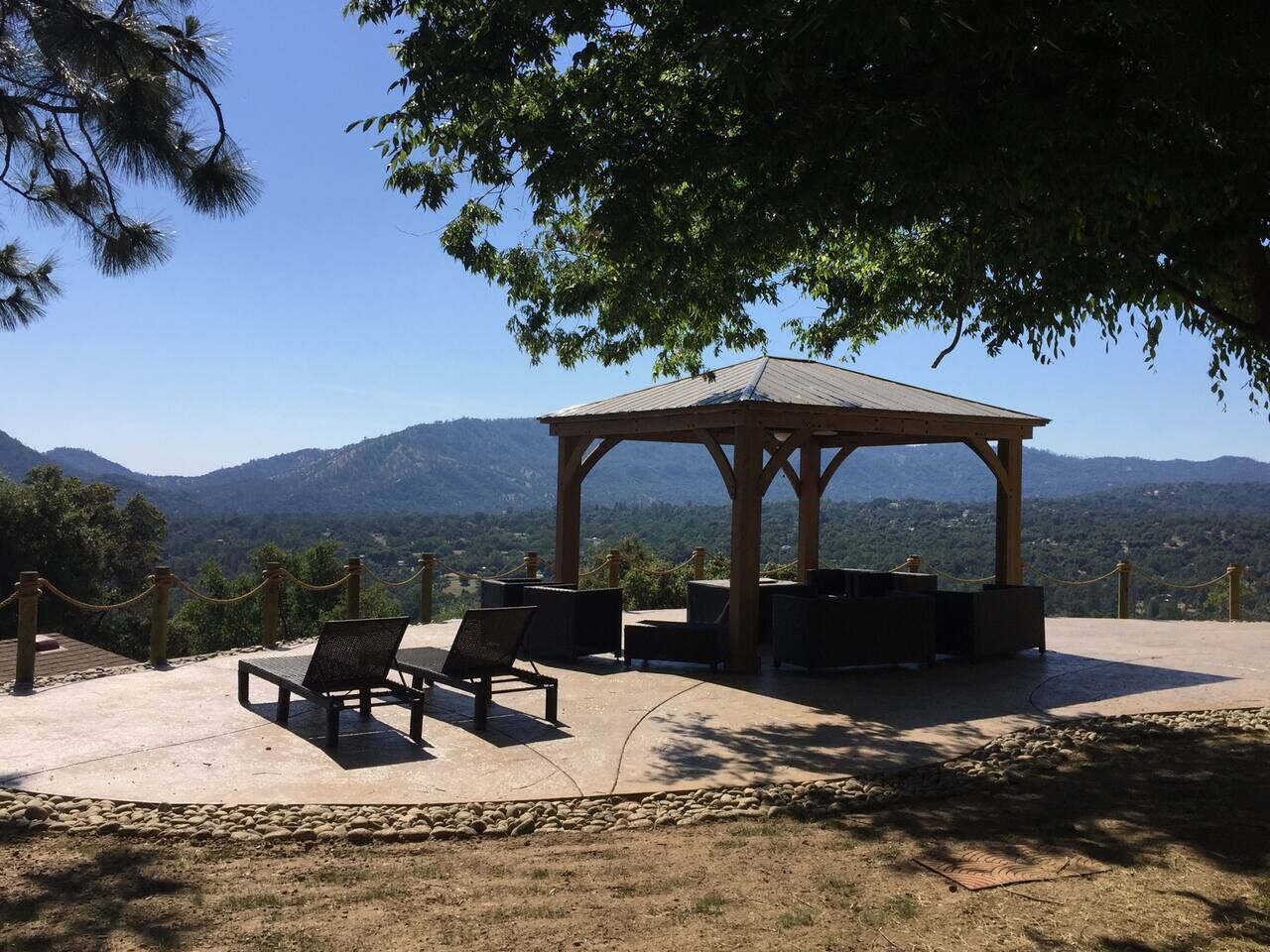 Un espace extérieur aménagé avec un belvédère, des tables et des chaises, offrant une vue sur un paysage montagneux.