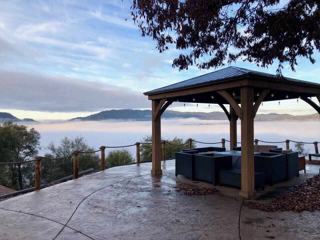 Ein überdachter Außenbereich mit Blick auf eine nebelverhangene Landschaft.