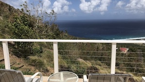Ein Balkon mit zwei Stühlen und einem Tisch mit Blick auf die Küste.