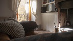 A cozy room with a bed, a TV, and a fireplace. - Cosy Medieval Townhouse, between lake, sea, thermal baths, Rome, Viterbo, Umbria (Anguillara Sabazia)