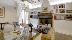 A cozy living room with a fireplace, a dining table with candles, and a bookshelf. - Cosy Medieval Townhouse, between lake, sea, thermal baths, Rome, Viterbo, Umbria (Anguillara Sabazia)