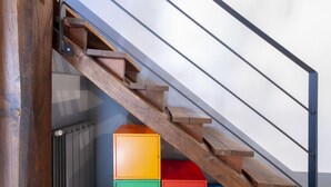 A wooden staircase with a metal railing, leading to a landing with colorful storage boxes. - Cosy Medieval Townhouse, between lake, sea, thermal baths, Rome, Viterbo, Umbria (Anguillara Sabazia)