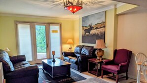 A living room with a sofa, armchair, coffee table, and a rug. There is a painting on the wall and a lamp on a side table. - CASCADE RETREAT MOUNTAIN VIEWS, GREAT LOCATION NEAR COLORADO SPRINGS ATTRACTIONS (Cascade-Chipita Park)