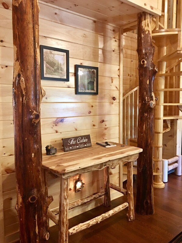 L’intérieur d’un chalet rustique, avec un bureau en bois, des photos encadrées et une enseigne portant l’inscription « The Cabin ».