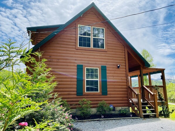 A wooden cabin with a porch and a staircase leading to the entrance.