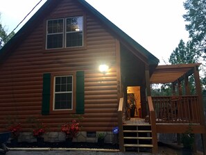 A log cabin with a porch, a staircase leading to the entrance, and a sign indicating ADA compliance.