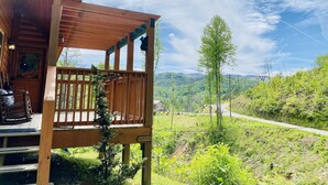 Una cabaña de madera con un porche que da a un paisaje montañoso.