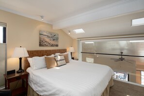 Ett hotellrum med en stor säng, två sänglampor, en takfläkt och utsikt över balkongen.