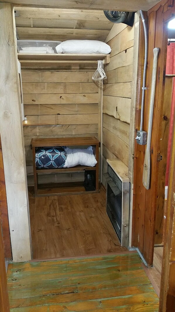 Una baita di legno con una panchina, un termosifone e una porta con un asciugamano appeso.
