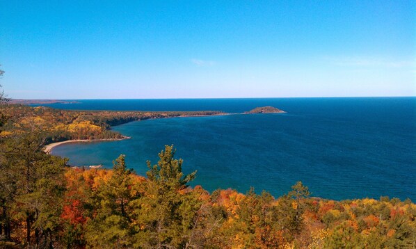 A coastal landscape with dense forest and a clear view of the sea.