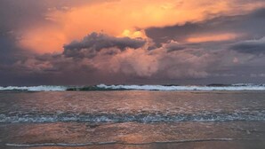 Une plage avec des vagues et un ciel au coucher du soleil.