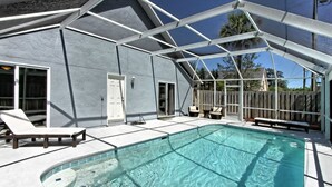 Une piscine extérieure couverte, dotée de chaises longues et d’un espace patio.