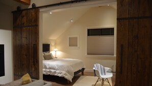Een slaapkamer met een bed, een stoel, een lamp en een raam met jaloezieën.