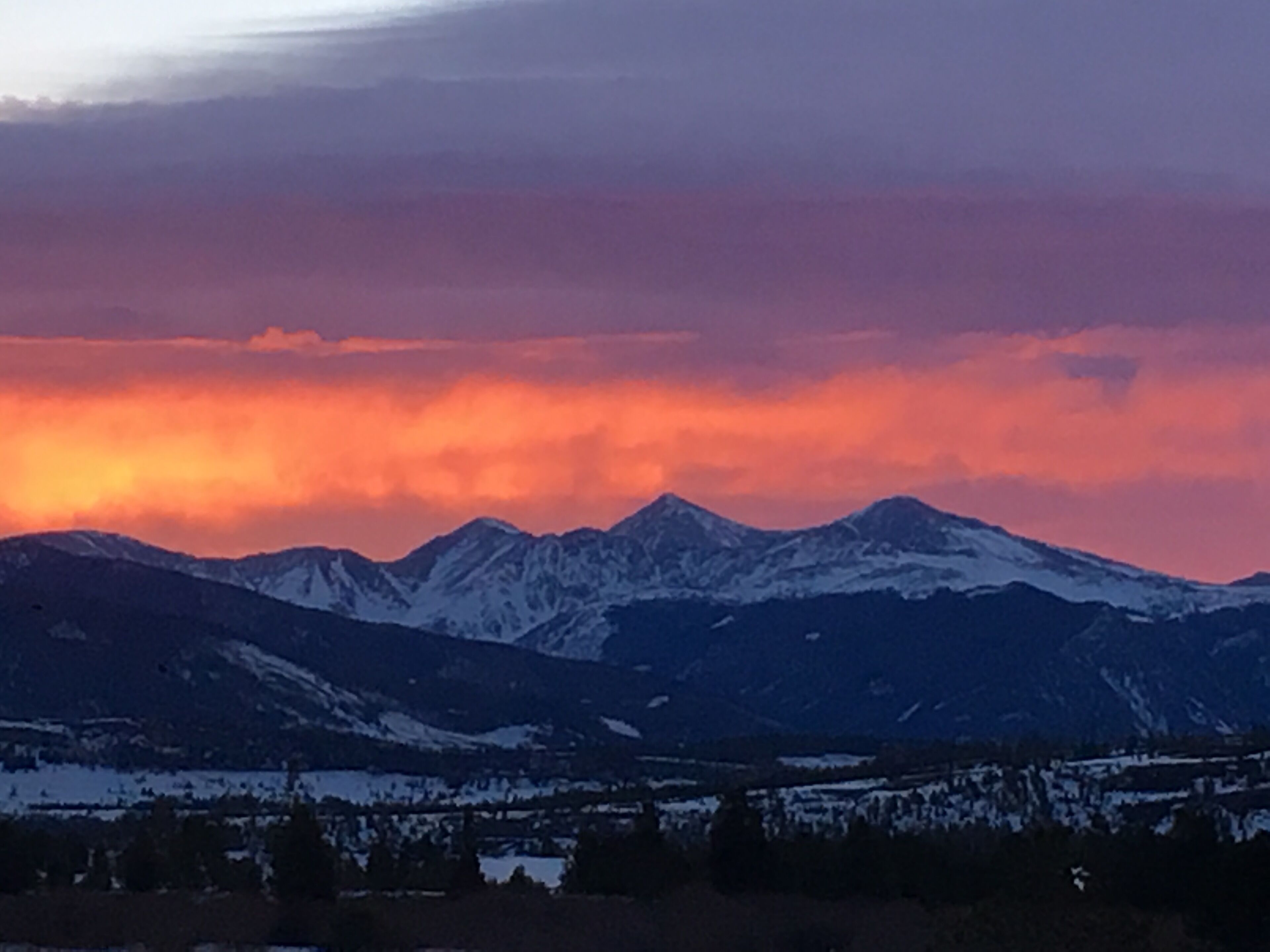 A mountain range with snow-capped peaks and a valley below.