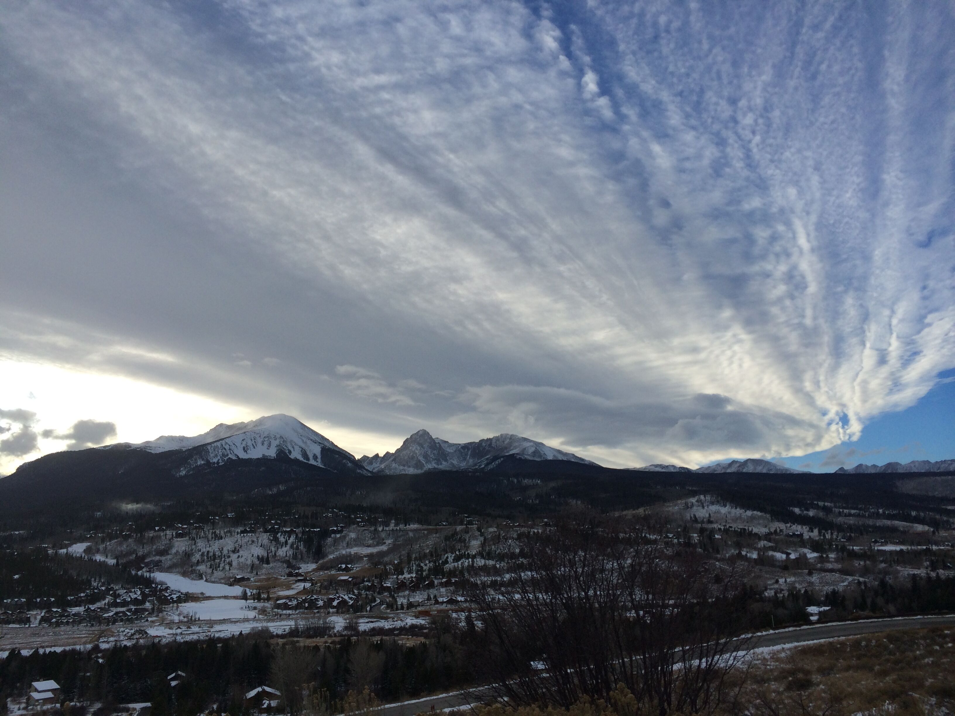 Paesaggio montuoso con cime innevate e una città in basso.