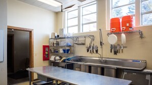 Una cocina con electrodomésticos de acero inoxidable, una mesa grande y un ventanal con vistas a árboles.
