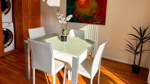 A dining area with a glass table and white chairs, a painting on the wall, and a potted plant. - Beachy Private Get-A-Way!! Large Deck facing Ocean! (Playa Del Rey)