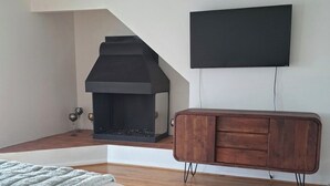 A bedroom with a bed, a fireplace, a TV, and a wooden cabinet. - Beachy Private Get-A-Way!! Large Deck facing Ocean! (Playa Del Rey)