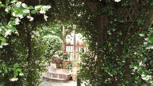 A garden with a wooden pergola, stone steps, and potted plants. - The Shebeen A small Irish cottage,come experience the enchantment and trnquility (Brooksville)
