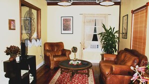 A living room with two leather sofas, a coffee table, a potted plant, and a fireplace. - The Shebeen A small Irish cottage,come experience the enchantment and trnquility (Brooksville)