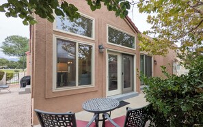 A two-story building with large windows and a patio area with a table and chairs.