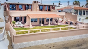 Un edificio de dos pisos con un patio, asientos exteriores y vistas del barrio.