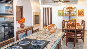 Una cocina con salpicadero de azulejos, una estufa y un comedor con mesa y sillas de madera.