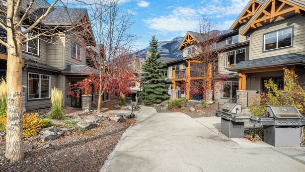 A residential street with houses, a central walkway, and a mountain in the background. - Copperstone 2BR in the Canadian Rockies - Dog-Friendly, Shared Hot Tub (Dead Man's Flats)