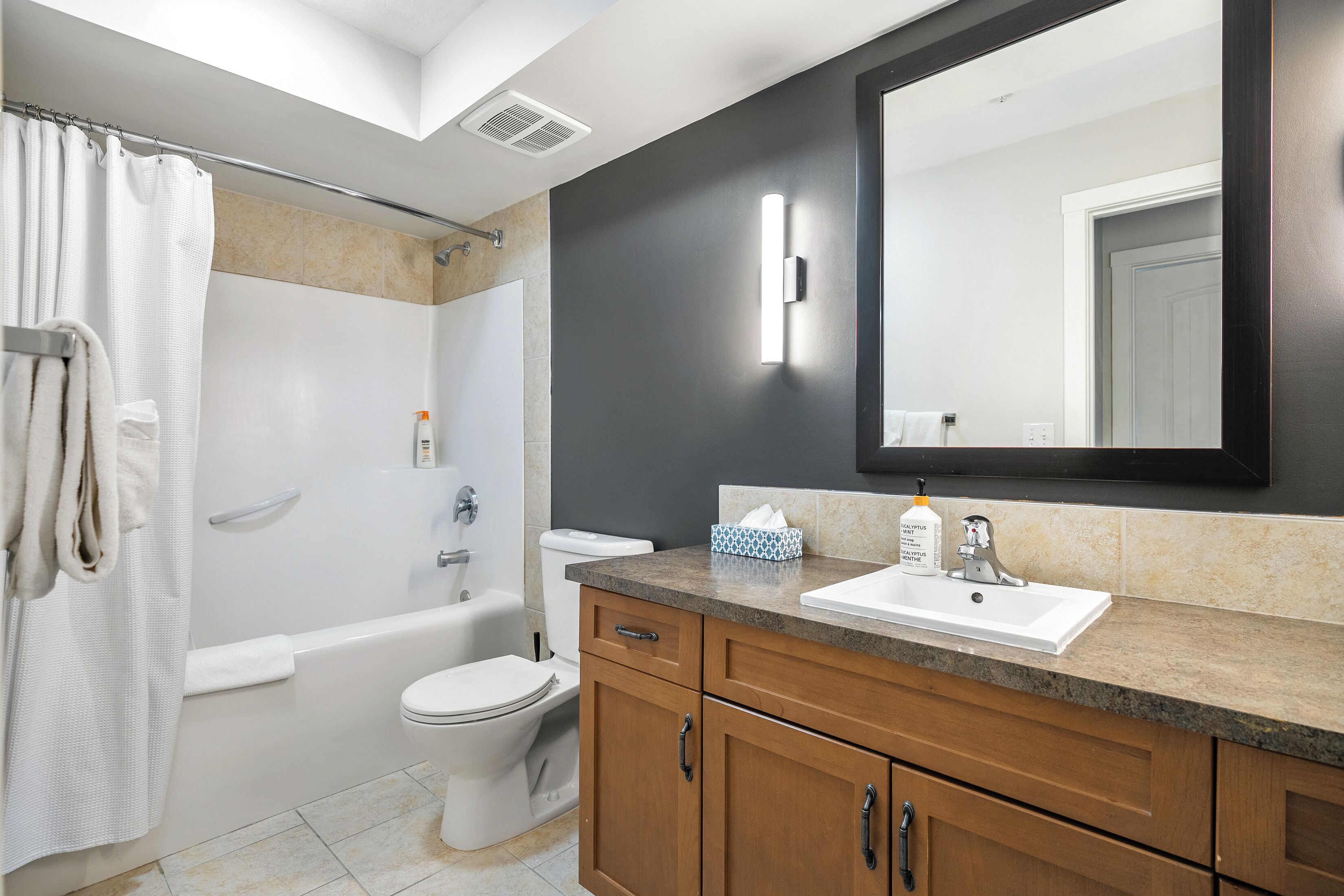 A modern bathroom with a bathtub, toilet, and vanity with a sink.