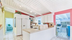 Une cuisine moderne avec des meubles blancs, un îlot central et un mur d’accent rouge.