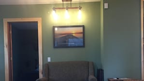 A living room with a sofa, a coffee table, and a painting on the wall. - Year Round Lakeview Cottage with Dock on Lake Champlain (Alburg)