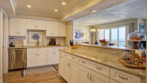 A spacious kitchen with white cabinets, granite countertops, and a built-in dishwasher. - Breathtaking Penthouse w/ Direct Oceanfront Views,  40' private balcony. (Daytona Beach Shores)