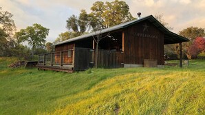 Ein rustikales Holzgebäude namens 'Copper Lodge' mit überdachter Veranda und einer kleinen Holzterrasse.