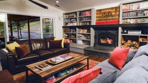 Ein Wohnzimmer mit Kamin, Bücherregalen, einer Couch und einem Couchtisch.