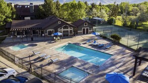 Ein Poolbereich mit zwei Pools, Liegestühlen, Sonnenschirmen und Blick auf Berge.