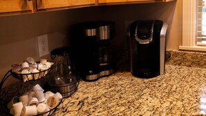 Eine Küche mit Holdekor-Schränken, einer Kaffeemaschine und einer Kaffeekanne auf einer Arbeitsplatte aus Granit.