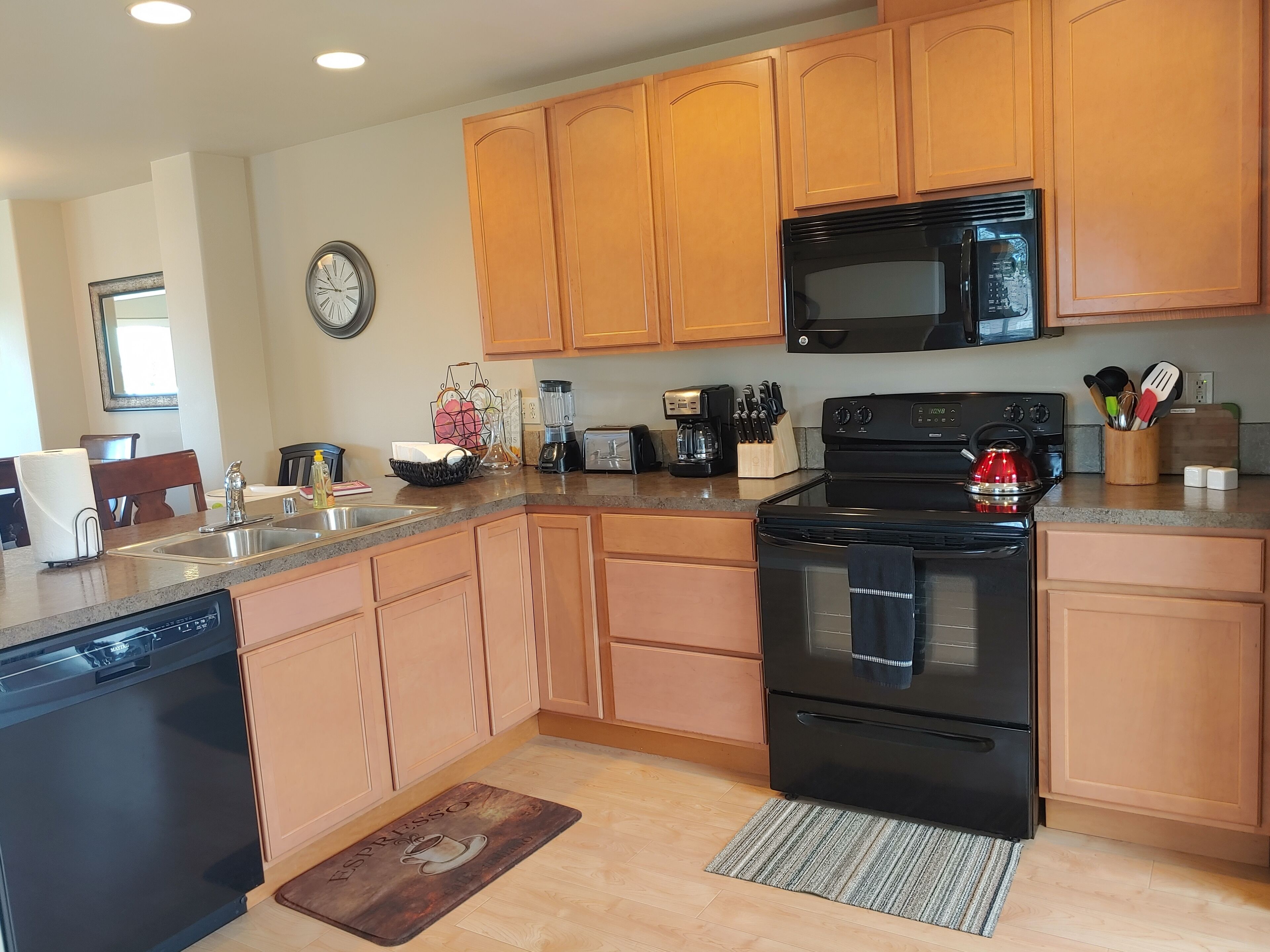 A kitchen with wooden cabinets, a black stove, a microwave, and a coffee maker.