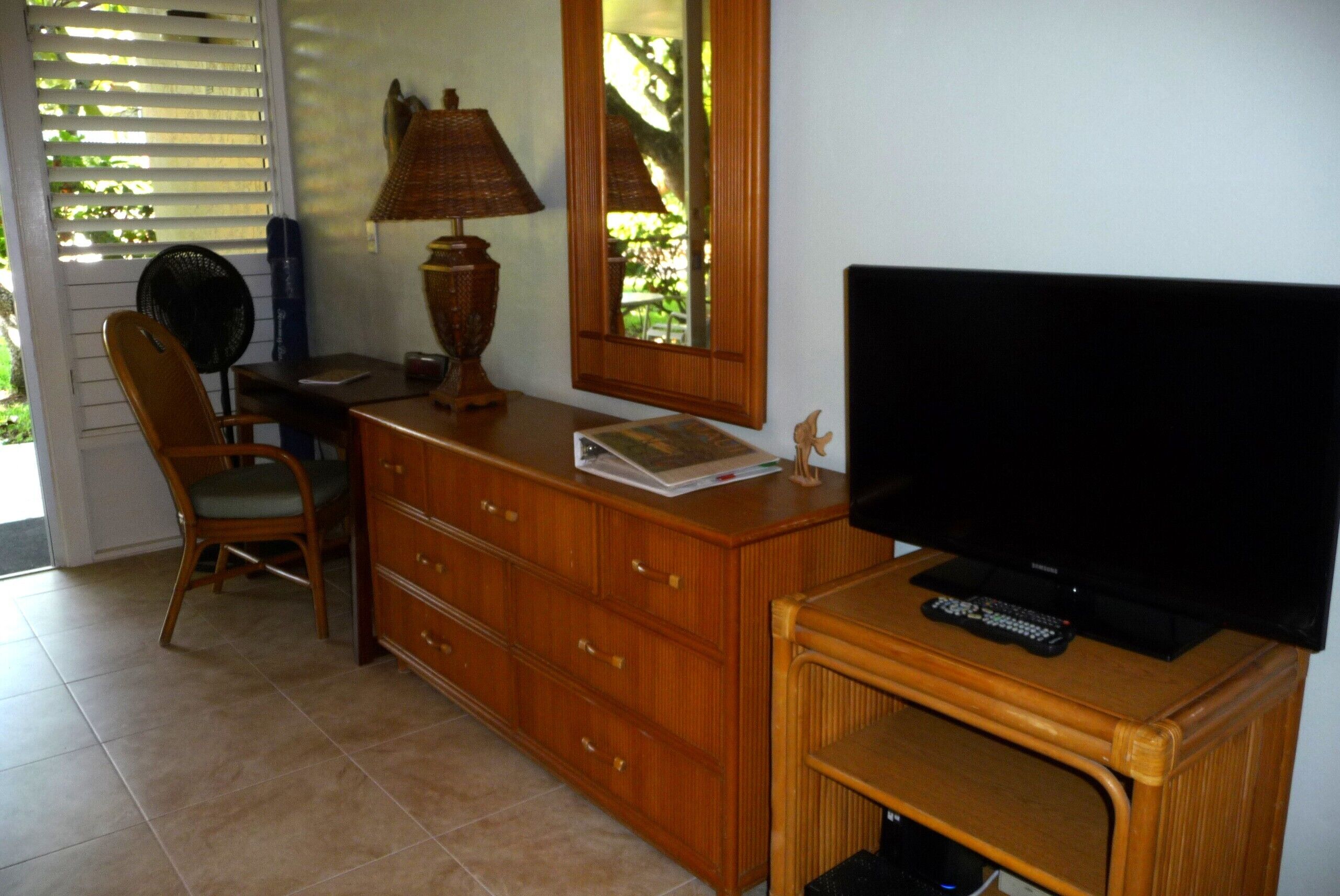A wooden dresser with a television, a lamp, and a mirror.