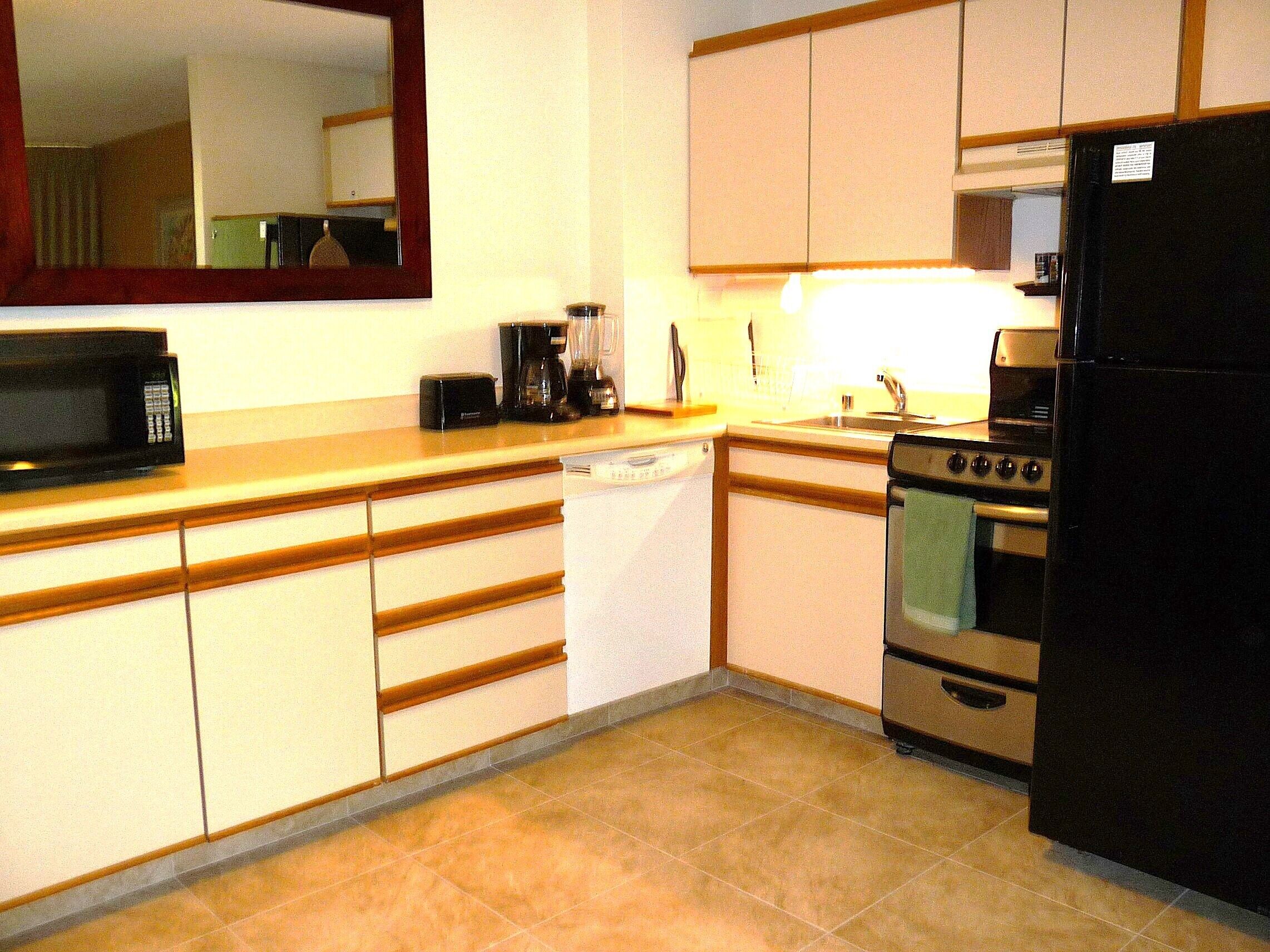 A compact kitchen with a microwave, coffee maker, toaster, and a refrigerator.